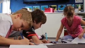 Three children reading and writing.